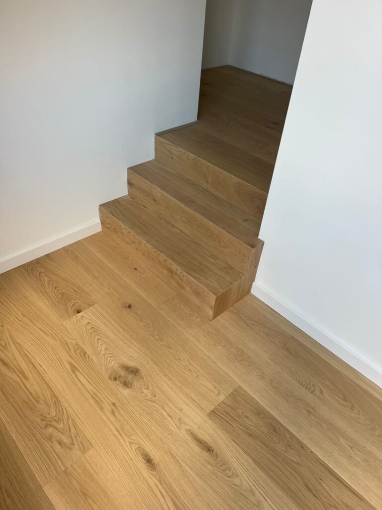 Vloertopper legt laminaattrap met houtnerfstructuur.